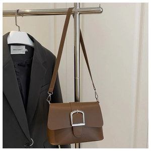 Detailed view of brown leather bag with silver D-buckle and matching leather strap