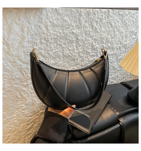 Detailed view of black crescent bag featuring vertical pleated leather and gold zippers