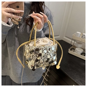 Detail of sequin drawstring bucket bag featuring metallic gold and silver finish and chain