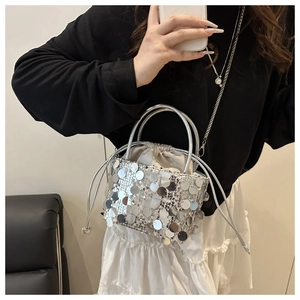 Detail view of silver sequin bucket bag with drawstring closure and metal chain strap