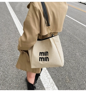 Detailed macro view of woven raffia tote bag texture with chain leather shoulder strap