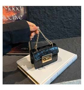 Dettaglio mini borsa nera stampa coccodrillo con catena d'oro e fibbia metallica