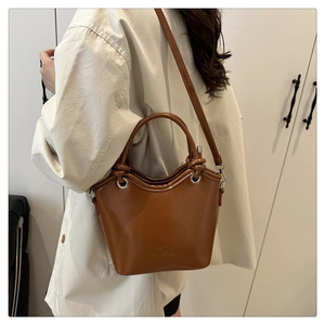 Detailed view of the brown glossy bucket bag with handle and embossed front logo