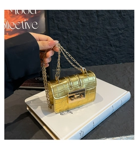 Dettaglio mini borsa squadrata dorata a coccodrillo con chiusura e tracolla a catena