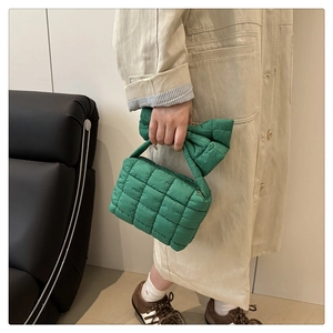 Detailed close-up of green quilted cloud bag with large bow handle and puffy texture