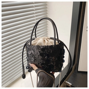 Detailed close-up of a black sequin bucket bag with drawstring and silver chain strap