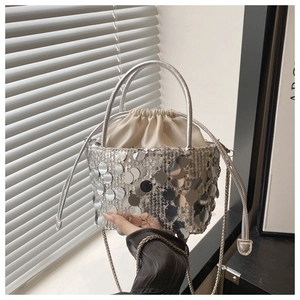 Detail of silver sequin bucket bag featuring drawstring closure and metal chain strap