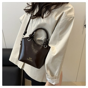 Detail of dark brown glossy patent leather handbag styled with a crossbody strap