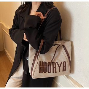 Detail showing the HOORYA canvas tote bag with brown leather straps on a black blazer