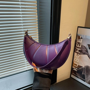 Purple crescent shoulder bag with quilted texture and metal zipper in hand