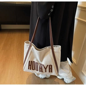 Detail of canvas tote bag featuring brown leather straps and HOORYA letter logo