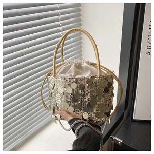 Detail of golden sequin bucket bag with metal handle, drawstring silk lining and chain strap