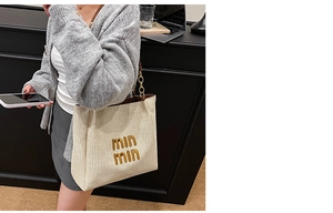 Detail of knit tote bag featuring gold embroidery and stylish brown chain shoulder strap