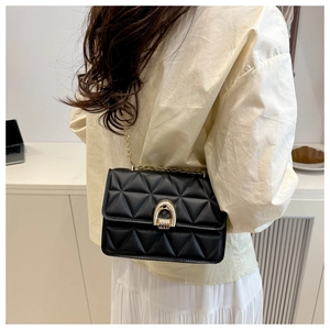 Détail du sac à bandoulière en cuir matelassé noir avec chaîne dorée et fermoir en métal