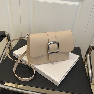 Minimalist cream leather crossbody bag with silver buckle and sleek shoulder strap