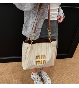 Detail shot of the large woven tote bag featuring contrast straps and branded embroidery
