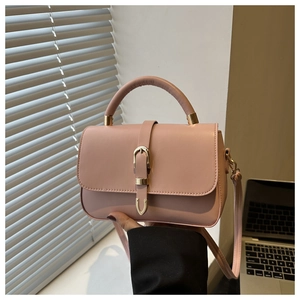 Détail d'un petit sac carré rose clair avec boucle dorée et bandoulière amovible