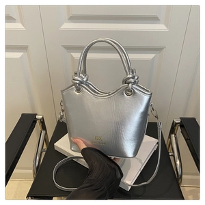Macro shot of silver metallic bucket bag with wave top and knot handle detail