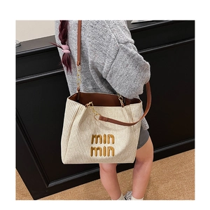 Detail of woven tote bag with brown leather strap and min min embroidery accents