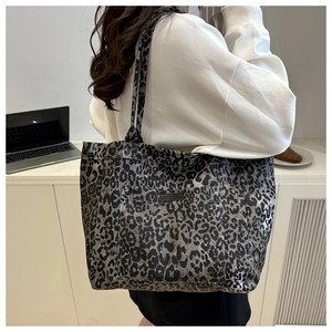 Close-up of leopard print canvas tote bag with black logo patch and durable handles