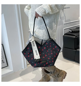 Detail of large tote bag featuring cherry print, long ribbon strap and brand logo