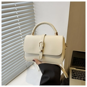 Détail d'un sac à main en cuir blanc crème avec boucle métallique élégante et poignée