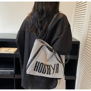 Detail of grey canvas tote bag with black leather straps and HOORAYA embroidery