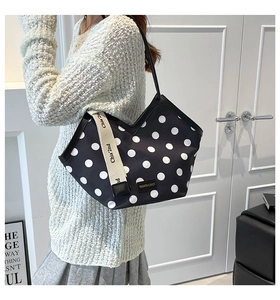 Detail of black and white polka dot tote bag with lettered strap and chic side design