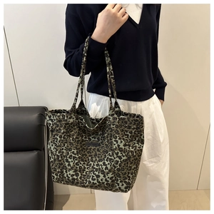 Detailed view of the leopard print canvas tote bag featuring a stitched label and wide straps