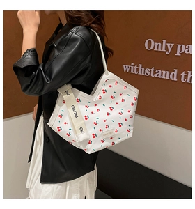 Detail of canvas tote bag with cherry print and branded wide fabric shoulder strap