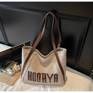 Detail of white canvas tote bag with brown leather straps and HOORAYA embroidery