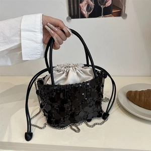 Elegant bucket bag with black sequins and satin drawstring insert on a café table