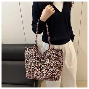 Close-up of pink leopard print canvas tote bag featuring black logo patch and durable straps