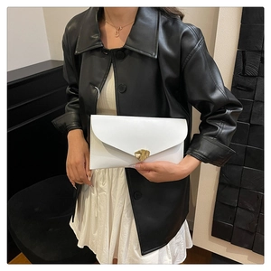 Close-up of white envelope clutch with gold buckle detail and smooth leather texture