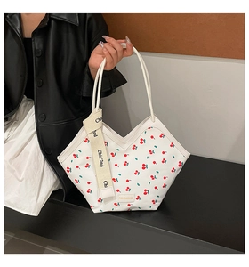 Close-up of canvas bucket bag with cherry print and branded fabric label detail