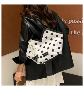 Close-up of black and white polka dot tote bag with wide canvas shoulder strap details