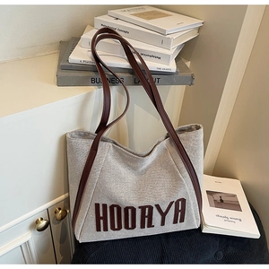 Detailed close-up of canvas texture and brown leather straps on an off-white tote bag