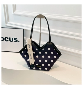 Detail of navy blue polka dot tote with V-cut edge and decorative lettered ribbon