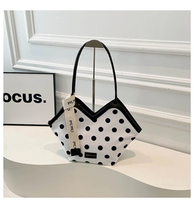 Detail of white polka dot bucket bag featuring unique V-shaped opening and brand ribbons