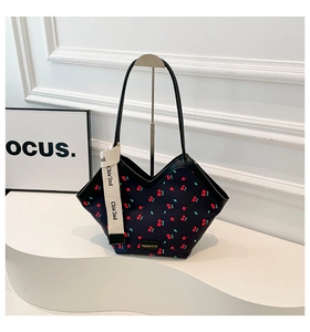 Close-up of a stylish black tote bag featuring red cherry prints and unique V-shaped opening