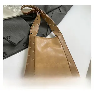 Vue détaillée du sac en cuir camel avec œillets dorés sur une veste de costume grise