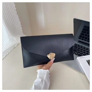 Detail of elegant black envelope clutch bag featuring wavy gold metallic magnetic clasp