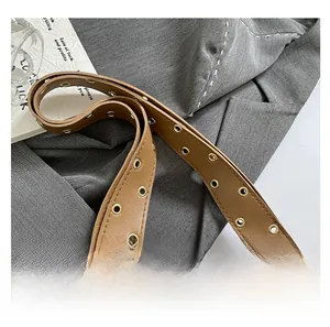 Détail de la bandoulière en cuir marron avec œillets dorés pour sac d'épaule moto