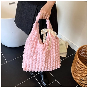 Detail of pink bubble texture fabric with beige lace bow on a stylish tote handbag