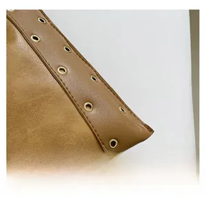 Gros plan d'un sac cabas en cuir marron avec double texture et détails d'œillets dorés