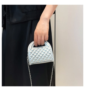 Detailed view of silver quilted crossbody bag with metal chain strap and top handle