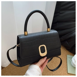 Detail of black faux crocodile leather baguette bag with golden hardware and top handle