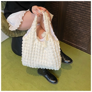 Detail of white cloud pleated tote bag showing bubbled texture and delicate lace bow