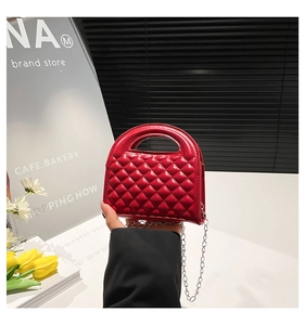 Detail of red quilted mini bag featuring a sleek hollow oval handle and silver chain strap