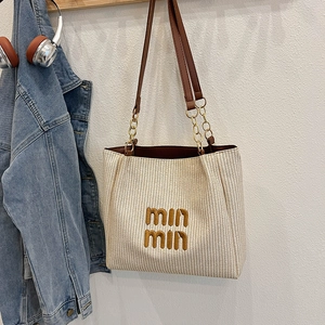 Large beige woven tote bag with chain straps and embroidery shown in a lifestyle scene